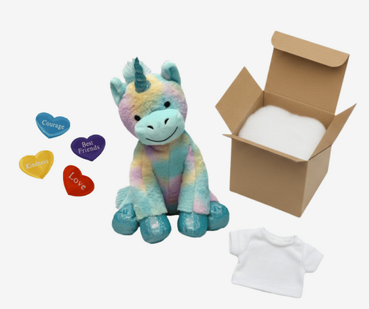 Colorful plush unicorn toy with heart-shaped tags, a cardboard box, and a white t-shirt on a white background.
